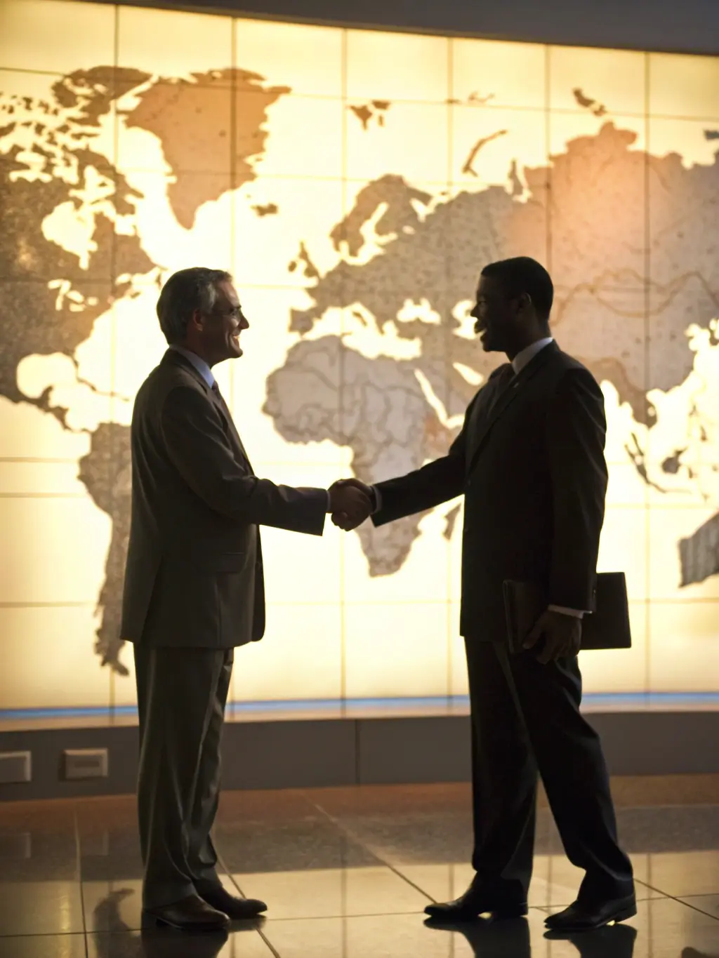 A handshake between two business partners in front of a world map, symbolizing international agreements and contract drafting.